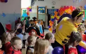 dzieci w strojach karnawałowych między nimi panie nauczycielki w przebraniach sala udekorowana