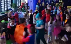 dzieci w strojach karnawałowych na sali udekorowanej w serpentyne i balony
