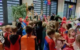 dzieci w przebraniach karnawałowych na sali udekorowanej balonami serpentynami