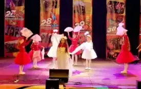 dziewczynki w białych i czerwonych sukienkach na scenie w tle banery Wielkiej orkiestri świątecznej pomocy