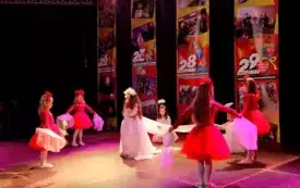 dziewczynki w białych i czerwonych sukienkach na scenie w tle banery Wielkiej orkiestri świątecznej pomocy