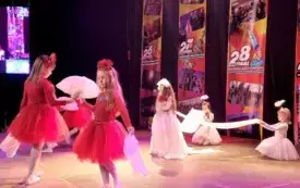 dziewczynki w białych i czerwonych sukienkach na scenie w tle banery Wielkiej orkiestri świątecznej pomocy