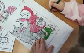ręce dziecka na stole kolorowy obrazek z czerwonym kapturkiem i wilkiem