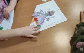 dzieci przy stoliku na stoliku obrazki pokolorowane i ułożone z kilku element&oacute;w