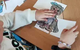 dziecko przy stoliku przed nim pokolorowany obrazek kota w kawałkach
