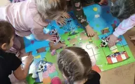 dzieci pochylone nad układanką zkolorowych puzzli siedzą na podłodze