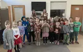 grupa dzieci pozuje do zdjęcia za nimi dwie panie z kotami na rękach
