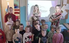 grupa dzieci pozuje do zdjęcia za nimi panie z kotami tablica multimedialna obok pani nauczycielka