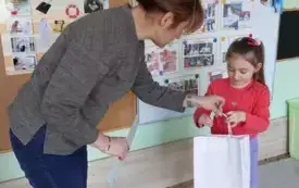 dziewczynka otrzymuje od nauczycielki dyplom i torebkę prezentową