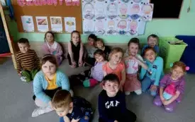 grupa dzieci na tle dekoracji tłusty czwartek i prac plastycznych człowiek jedzący donata