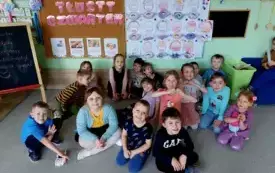 grupa dzieci na tle dekoracji tłusty czwartek i prac plastycznych człowiek jedzący donata
