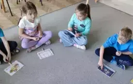 dzieci siedzą na dywanie przed nimi obrazki z pączkami 