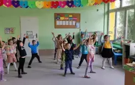 dzieci stoją na dywanie z rękami uniesionymi do g&oacute;ry