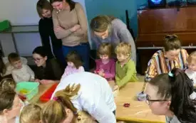 dzieci i dorośli przy stolikach z masami sensorycznymi