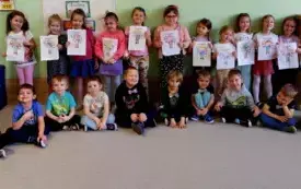 grupa dzieci pozuje do zdjęcia dziwczynki trzymają laurki chłopcy mają przyczepione kolorowe muszki