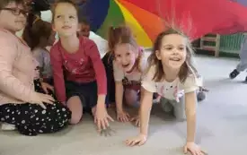 dziewczynki z naelektryzowanymi włosami siedzą pod kolorową chustą animacyjną