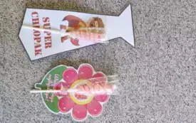 papierowy krawat z napisem super chłopak i przyczepionym lizakiem papierowy kwiat z napisem wszystkiego najlepszego i z przyczepionym lizakiem