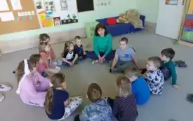 dzieci i nauczycielka siedzą w kole na dywanie
