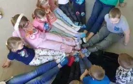 dzieci siedzą w kole łącząc się stopami w środku na stopach kolorowe skarpetki