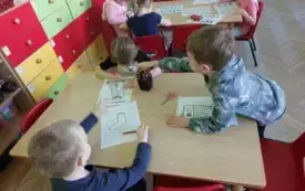 dzieci przy stoliku przed nimi karty pracy z motywem skarpetek