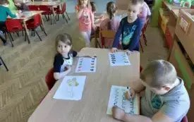 dzieci przy stolikach, przed nimi karty pracy z motywem skarpetek