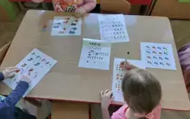 dzieci przy stoliku uzupełniają karty pracy z wzorami skarpetek