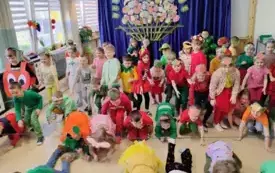 grupa dzieci na sali wzdł&oacute;ż nich rozciągnięta lina na wysokości kolan dzieci w kolorowych owowcowo warzywnych strojach