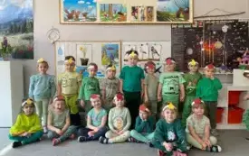 grupa dzieci w opaskach z jabłkami i gruszkami pozuje na tle dekoracji wiosennej