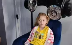 dziewczynka siedzi na fotelu nad nią lampy fryzjerskie