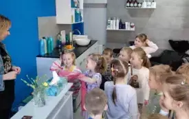 wnętrze salonu fryzjerskiego pani fryzjerka stoi za ladą dzieci patrzą na panią fryzjerkę