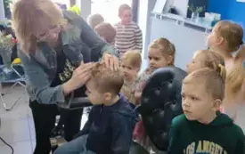 pani fryzjerka czesze chłopca dzieci przyglądają się