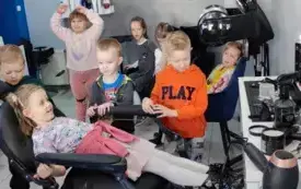 dzieci w salonie fryzjerskim dziewczynka siedzi na fotelu widać przybory fryzjera z nimi pani