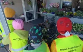 czw&oacute;rka dzieci przed sklepem ogrodniczym w tle kwiaty dekoracje i wejście do sklepu
