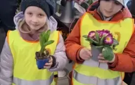 chłopiec i dziewczynka trzymają kwiatyw doniczkach stoją w sklepie ubrani w kamizelki odblaskowe