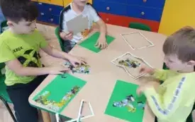 dzieci siedzą przy stoliku przed nimi puzzle