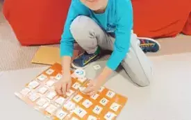 chłopiec siedzi na dywanie przed nim album z literami