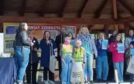 dzieci i dorośli stoją na podwyższonej scenie w tle pan prezydent miasta Zgierza