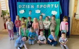 grupa dzieci pozuje do zdjęcia na tle dekoracji z napisem dzień sportu
