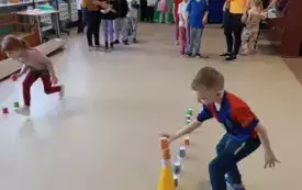 chłopiec nakłada kubki na ż&oacute;łty pachołek w tle dwie drużyny dzieci