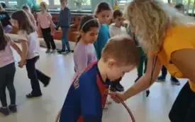 pani nauczycielka pomaga chłopcu przejść przez hula hop