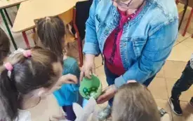 pani częstuje dzieci kolorowymi jajeczkami z opakowania w kształcie połowy skorupy jaja
