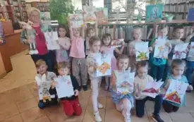 grupa dzieci pozuje do zdjęcia z panią z biblioteki dzieci trzymają swoje prace plastyczne zajączki wycinanki