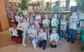 grupa dzieci pozuje do zdjęcia z panią z biblioteki dzieci trzymają swoje prace plastyczne zajączki wycinanki