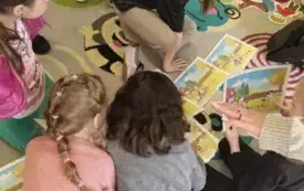 dzieci siedzą na dywanie pomiędzy nimi leżą obrazki