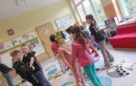 dzieci stoją w parach na dywanie dziewczynka ma na głowie opaskę rzepki