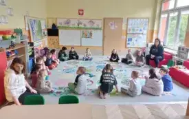 grupa dzieci siedzi w kole na dywanie z nimi dwie panie