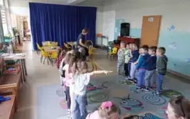 dzieci stoją na dywanie w dw&oacute;ch rzędach nauczycielka przed nimi trzyma kolorowe obręcze