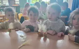 dzieci przy stoliku na kt&oacute;rym stoją gotowe dekoracje wykonane z pi&oacute;r skorupek od jajek itp