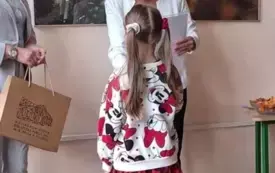 elegancko ubrana pani wręcza dyplom dziewczynce kt&oacute;ra stoi tyłem do zdjęcia