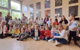 duża grupa dzieci pozuje do zdjęcia niekt&oacute;re dzieci trzymają dyplomy w tle i obok panie